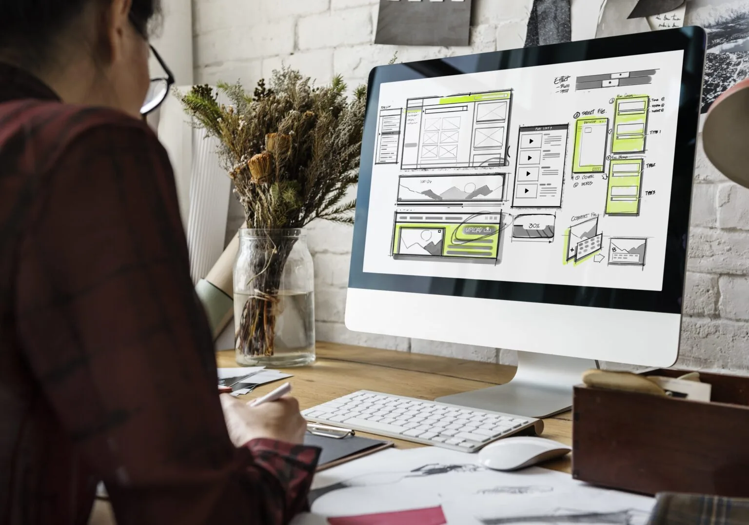 Website designer reviewing page wireframes on a desktop monitor